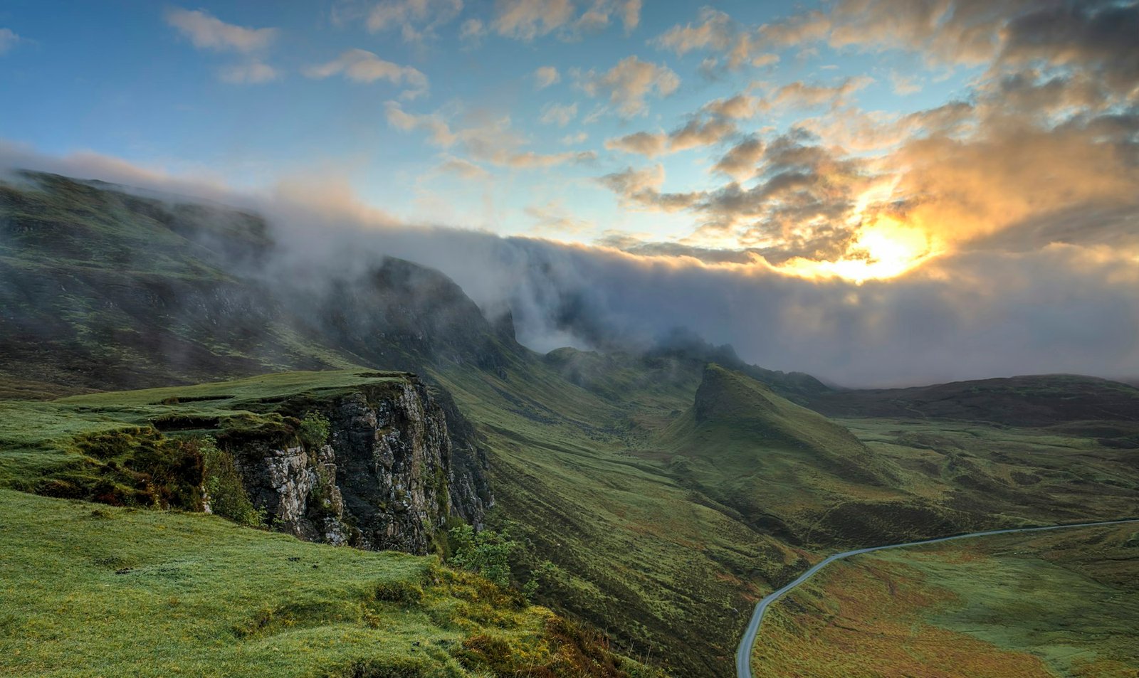 Sun breaking over a misty green landscape